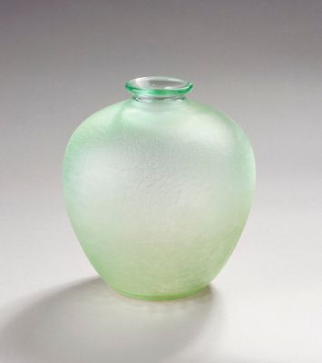 un vase en verre vert posé sur une surface blanche