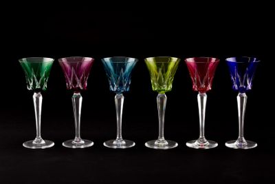 six different colored wine glasses lined up in a row on a black background