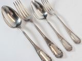 four silver spoons and a fork on a white surface