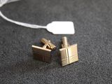 une paire de boutons de manchette en or avec une étiquette sur un fond noir