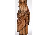 une statue en bois représentant un homme coiffé d'un chapeau et vêtu d'une robe