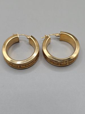 a pair of gold hoop earrings on a gray surface