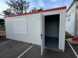a small white building with a red roof in a parking lot