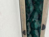 a close up of a metal object with a green stone in it