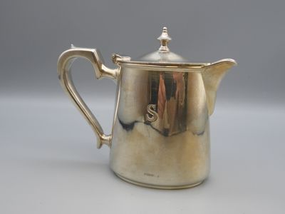 an antique silver coffee pot with a handle on a white surface