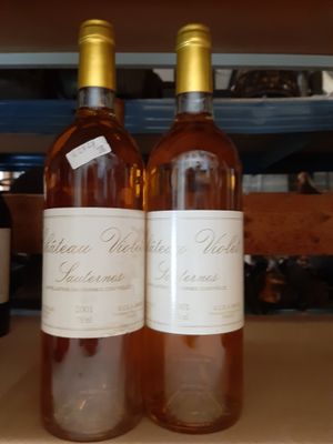 deux bouteilles de vin posées sur une étagère l'une à côté de l'autre