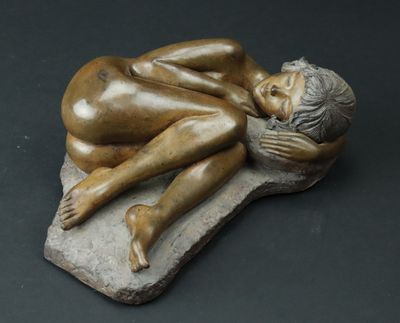 statue représentant une femme allongée sur un rocher, les mains sur le visage