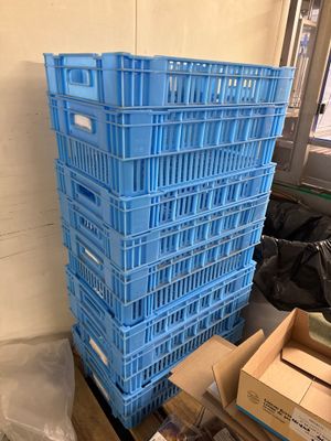 une pile de caisses bleues posées par terre près d'une fenêtre