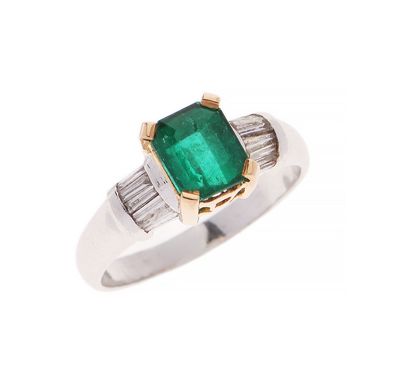 a close up of a ring with an emerald stone and baguets
