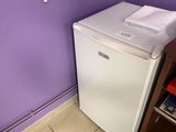 purple walls in a small room with a white refrigerator and a shelf