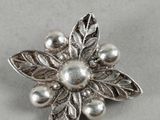 silver flower brooch with pearls on a white background