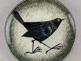 une petite assiette sur laquelle est représenté un oiseau, posée sur une table