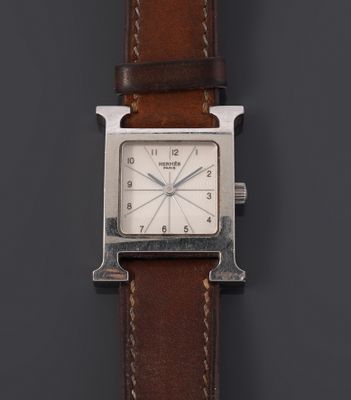 a close up of a watch on a black surface with a brown strap