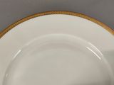 a white plate with a gold rim on a table