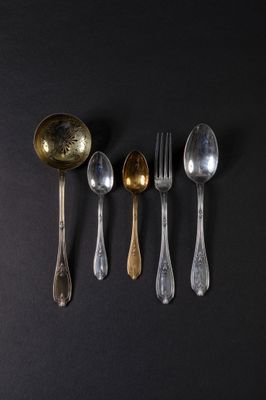 six spoons and a fork are arranged in a row on a black surface