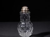 a small glass jar with a silver lid on a table