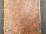 an old book with a brown cover sitting on top of a table
