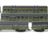 six green train cars sitting next to each other on a white surface