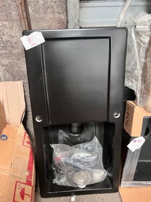 une boîte noire recouverte d'un sac en plastique, posée à côté d'une pile de boîtes