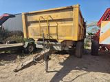 un camion-benne jaune garé sur un terrain en terre battue