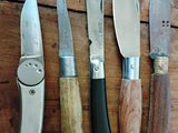 cinq types de couteaux différents posés sur une table en bois