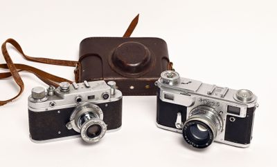two cameras sitting next to each other on a white surface