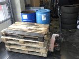 une palette sur laquelle sont posés deux fûts bleus, dans un garage