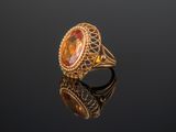un gros plan d'une bague en or sertie d'une pierre orange