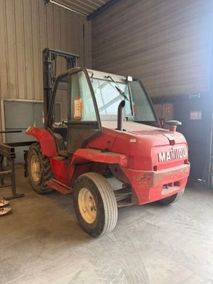 a red tractor parked inside of a building in a garage