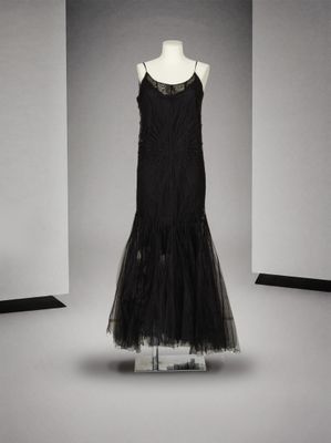 une robe noire posée sur un présentoir à mannequin dans une pièce