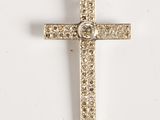 une croix en or ornée d'un diamant au centre, sur fond blanc