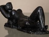 a statue of a woman laying down on a glass table