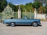 a blue convertible car parked in front of a gate