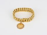 a close up of a gold bracelet with a medallion on it