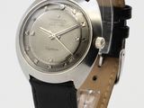a silver watch with black leather strap on a clear stand