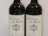 two bottles of red wine sitting on top of a white table