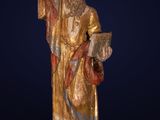 une statue représentant un homme vêtu d'une robe dorée et tenant un livre