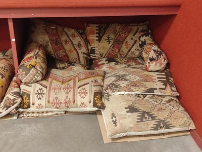 many pillows and pillows on the floor under a shelf