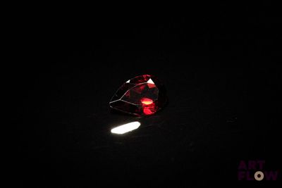 un gros plan d'une pierre rouge en forme de cœur posée sur une surface noire