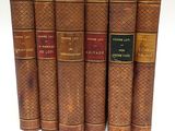 six vieux livres sont alignés sur une surface blanche