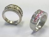 two wedding rings with pink and white diamonds on a white surface