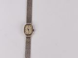 an old wrist watch sitting on top of a white surface