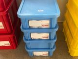 Dans une pièce, trois récipients en plastique sont empilés les uns sur les autres.
