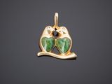 un pendentif en or représentant deux chats verts sur une branche