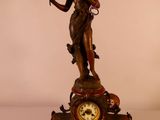 une statue représentant une femme tenant un oiseau à côté d'une horloge
