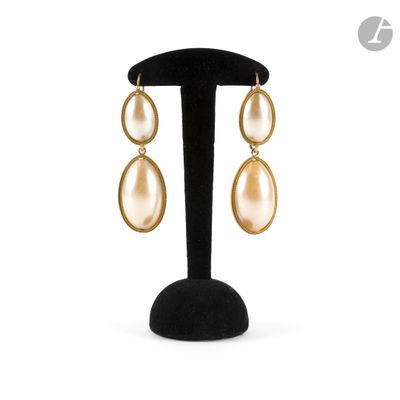 une paire de boucles d'oreilles en or ornées de perles, montées sur un support noir