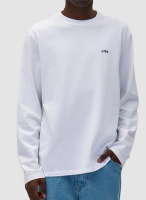 un homme vêtu d'un sweat-shirt blanc et d'un jean, debout devant un fond blanc