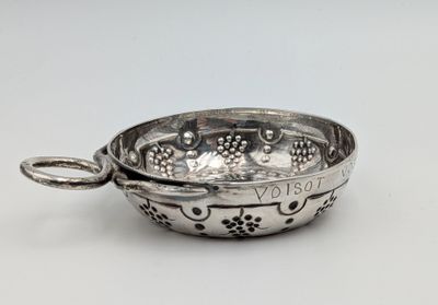 a silver bowl with a handle on a white surface