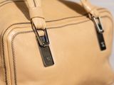 the large tan bag is sitting on the table next to the wall