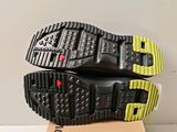 the soles of a pair of black and yellow shoes on top of a cardboard box